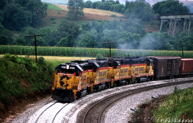 Familiar Territory
The corn is high, and the smell of diesel exhaust is heavy as Western Maryland GP40-2 #4318 leads a sister B&O unit and two GP30s in the assault upon Sandpatch Grade.  All three Chessie component roads are represented here, as the trailing GP30s carry B&O and C&O markings.  Could #4318 once have traveled across Salisbury Viaduct, seen in the upper right corner?  A lady never tells her age.
Photo Copyright 2008 Tim Baldwin
Keywords: salisbury;chessie;geeps;sandpatch;maryland;viaduct;bridge